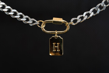 Gold chain jewelry with a gold earring and the letter H macro photography