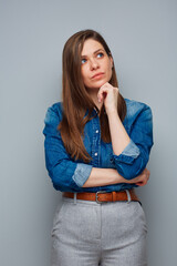 Wall Mural - Serious thinking woman in casual blue shirt looking up, isolated portrait.