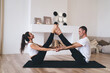 © BullRun - Couple practicing yoga with clasped hands in living room