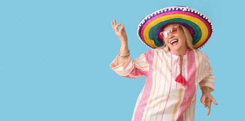 Wall Mural - Dancing mature Mexican woman in sombrero hat on light blue background with space for text