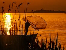 Silhouette Of A Person Fishing At Sunset