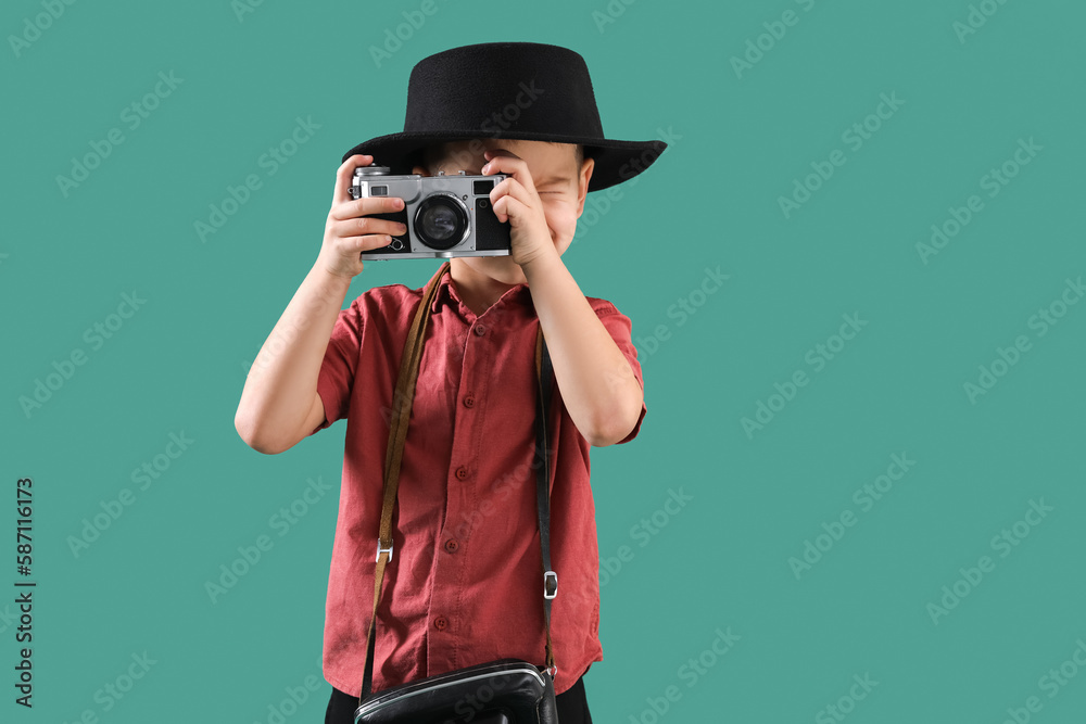 Cute little photographer with camera on green background