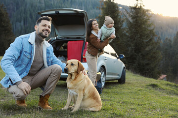 Canvas Print - Happy man with dog, mother and her daughter near car in mountains. Family traveling with pet