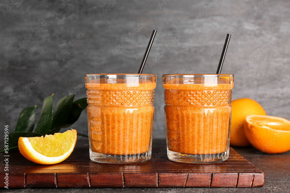 Glasses of healthy orange smoothie on dark background