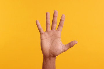man giving high five on yellow background, closeup of hand