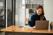 © Thitisak - ฺAsia Businesswoman sitting and working using laptop to chat with customers online in office