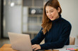 © Thitisak - ฺAsia Businesswoman sitting and working using laptop to chat with customers online in office