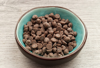 Wall Mural - Chunks of dark chocolate in a bowl on wooden background.