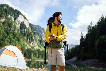 Wall Mural - Handsome happy backpacker man hiking, camping through mountain forest.