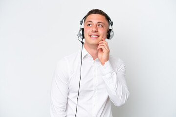 Wall Mural - Telemarketer Brazilian man working with a headset isolated on white background thinking an idea while looking up