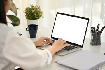 Businesswoman shoulder hand typing on keyboard of laptop computer. White screen for graphic display montage