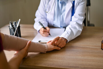 A female orthopedic doctor holding her patient hand to comfort and reassure during the meeting.