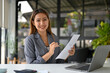 © bongkarn - Charming Asian businesswoman analyzing financial data on reports, working at her desk.