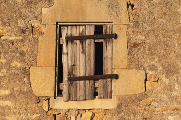 Abandoned stone buildings with an old window covered with wooden boards