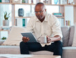 © Malik/peopleimages.com - Tablet, coffee and relax with a black man on the sofa, sitting in the living room of his home or office. Business, tech and research with a male employee reading an online article while on a break
