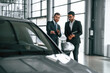 © standret - Looking at the vehicle. Man is consulting the customer in the car showroom