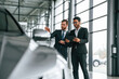 © standret - Looking at the vehicle. Man is consulting the customer in the car showroom