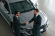 © standret - Doing handshake. Two businessmen are working together in the car showroom