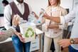 © luckybusiness - A group of employees is recycling the trash by collecting it in a bin in the office. Employees, job, office