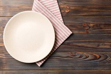 Top view on colored background empty round white plate on tablecloth for food. Empty dish on napkin with space for your design