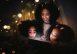Tablet, night a mother reading to her kids in a tent while camping in the bedroom of their home together. Black family, story or children with a woman storytelling to her kids at bedtime for bonding