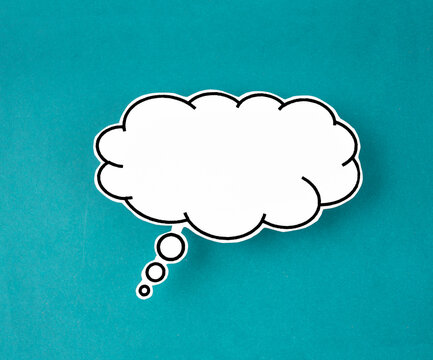 The White speech bubble shaped post it note on green background with copy space.