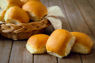 Wall Mural - Soft bread rolls on wooden table and wicker basket