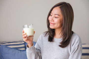 Wall Mural - Portrait image of a young woman holding and drinking fresh milk