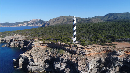 Wall Mural - Lighthouse by sea against mountains and sea 