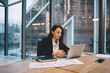 © BullRun - Focused businesswoman sitting at table and working on laptop in office