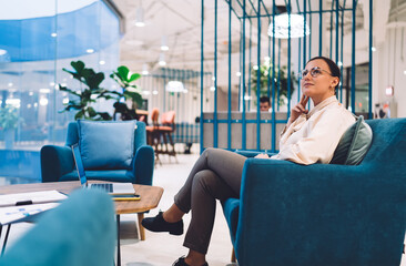 Poster - Pensive businesswoman sitting in armchair at office