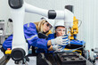 © gumpapa - female automation machine engineer student study and inspection control robot arm machine in university or factory workshop. ai robot technology new innovation trend of manufacturing in industry 5.0