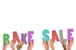 Cropped hands holding colorful words bake and sale 