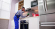 © Andrey Popov - Young Repairman Repairing Kitchen Extractor Filter
