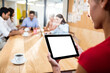 © vectorfusionart - Woman holding digital tablet with colleagues in background