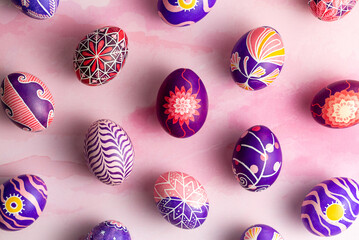 Pattern made of beautiful Easter eggs painted in pink, lilac and violet colors with unique design made of flowers, waves, sun and stars