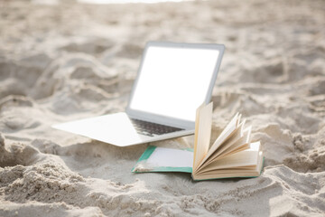 Poster - Open book and laptop on sand at beach 
