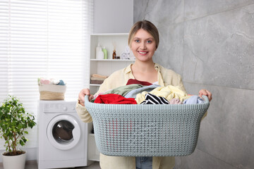 Wall Mural - Happy woman with basket full of laundry in bathroom