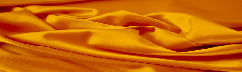 Wall Mural - Orange silk satin. Bright luxury background for design. Soft folds. Shiny golden draped fabric. Wavy lines. Flowing. Fluid, liquid, ripple effect. Fiery. Web banner. Wide. Panoramic.