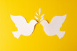 Close up of two white doves with leaf and copy space on yellow background