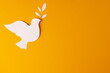 Close up of white dove with leaf and copy space on yellow background