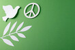 Close up of white dove and peace sign with leaves and copy space on green background