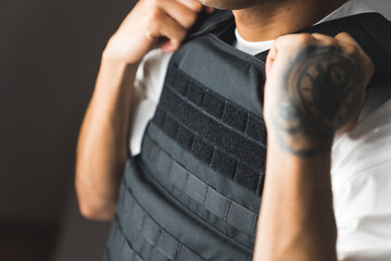 Closeup shot of tattooed man in white t-shirt and bulletproof vest. Protection and army concept. High quality photo