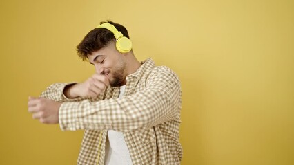 Sticker - Young arab man listening to music dancing over isolated yellow background