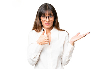 Wall Mural - Young caucasian woman over isolated chroma key background holding copyspace imaginary on the palm to insert an ad and with thumbs up