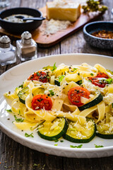 Wall Mural - Tagliatelle with parmesan, zucchini, tomato and cream sauce on wooden table
