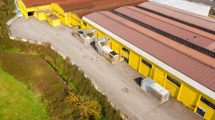 Wall Mural - Aerial view of a factory and its warehouses with yellow walls and an orange roof. The industrial area is empty and nobody is there.