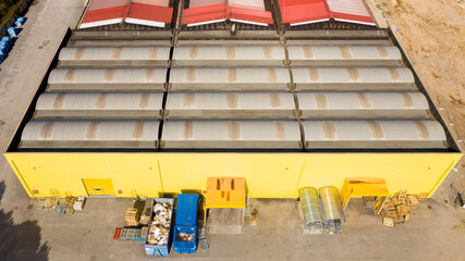 Wall Mural - Aerial view of a factory and its warehouses with yellow walls and an orange roof. The industrial area is empty and nobody is there.