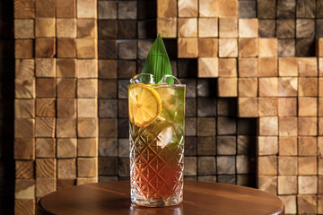 Wall Mural - An iced long drink cocktail in a highball glass garnished with lemon wheel and banana leaf