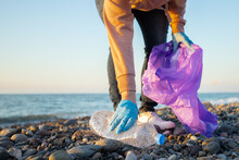Beach Cleaning, Woman Collects Plastic Garbage In A Bag On The Seashore, Volunteer Clean Up Trash